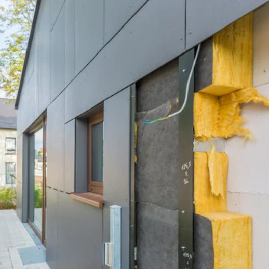 Hausfassade im Bau mit sichtbarer Mineralwolldämmung und montierten Außenpaneelen