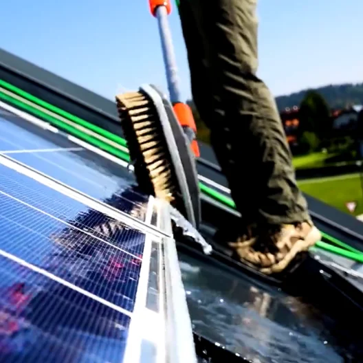 Reinigung von Photovoltaikmodulen auf einem Dach mit einer Langstiel-Bürste